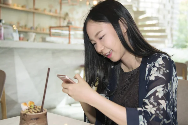 Asiatisk kvinna textning på den smarta telefonen när du sitter i coffe — Stockfoto