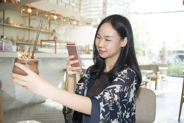 Mujer de Asia tomando una foto de su comida con su teléfono inteligente en cof —  Fotos de Stock