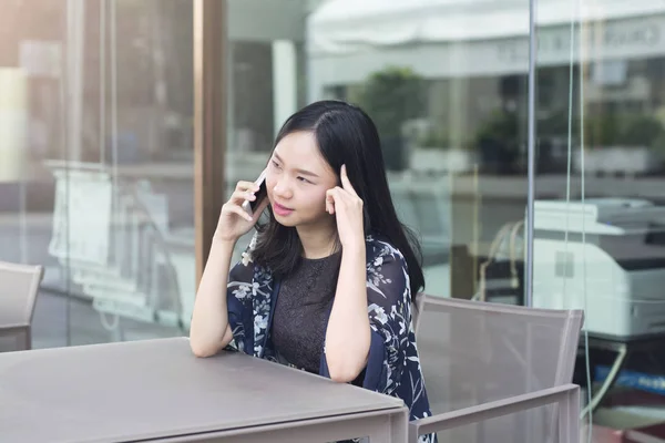 Asiatisk kvinna tänker när du ringer affären fodrar av smartphone — Stockfoto