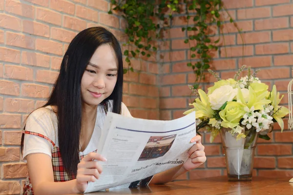 Asiática mujer leyendo periódico en oficina y sonrisa como fondo — Foto de Stock