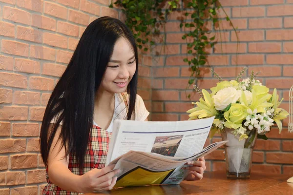 Asiática mujer leyendo periódico en oficina y sonrisa como fondo — Foto de Stock