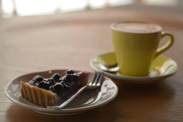 Šálek cappuccino kávu a borůvkový koláč sýr na stole v ca — Stock fotografie