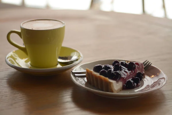 Šálek cappuccino kávu a borůvkový koláč sýr na stole v ca — Stock fotografie