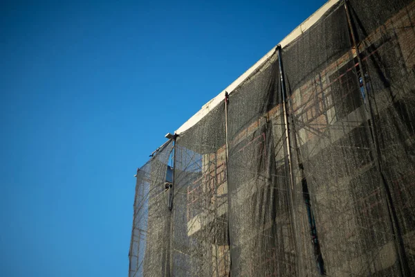 Byggande mellan byggnadsställningar med skuggat nätskydd — Stockfoto