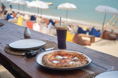 Pizza ve soğuk sade kahve teras tahtasına beac ile konur.