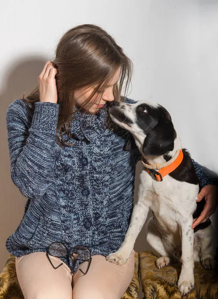 Jovem mulher atraente sorrindo enquanto segura um cão bonito — Fotografia de Stock
