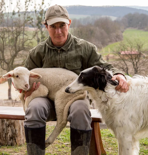 Bir adamın kollarında bir bebek kuzu portresi karşılamak ile köpek