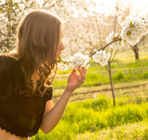 Hermosa chica morena disfrutar de un jardín de primavera con flor — Foto de Stock