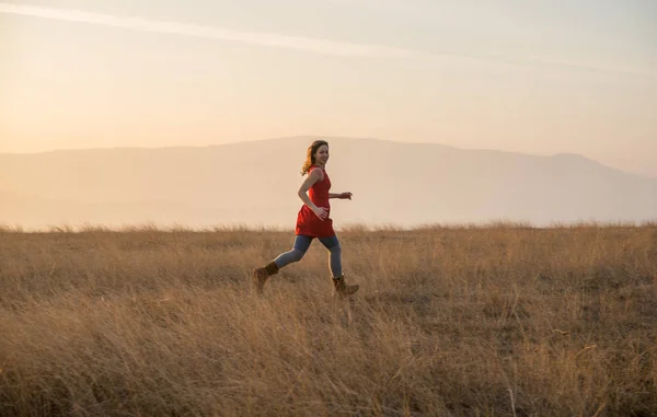 Schönes Mädchen läuft auf dem Feld in rotem Kleid — Stockfoto