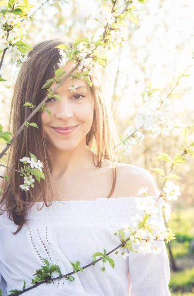 Hermosa chica morena disfrutar de un jardín de primavera con flor — Foto de Stock