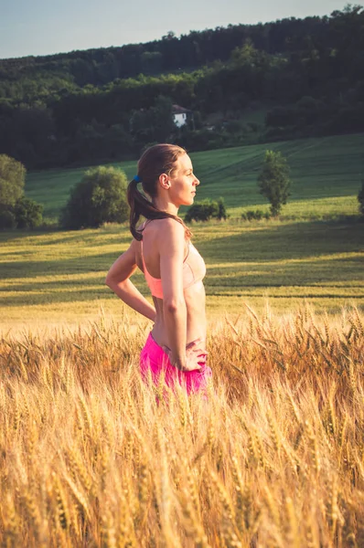 Schöne Läuferin in bunten Sportkleidung im Weizenfeld — Stockfoto