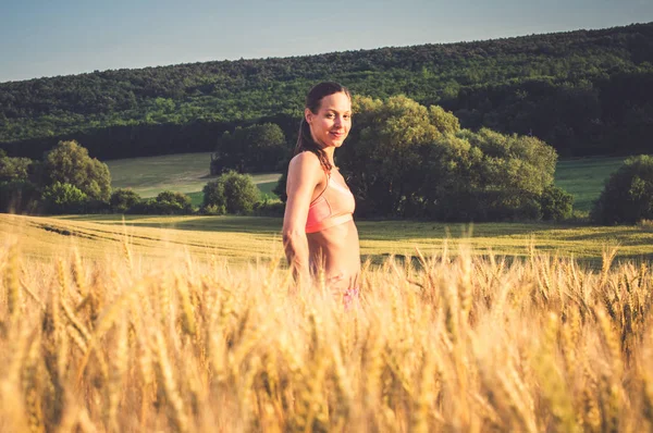 Schöne Läuferin in bunten Sportkleidung im Weizenfeld — Stockfoto