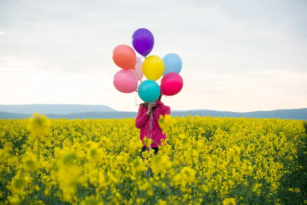 Beautiful woman with colorful balloons in field — Stock Photo, Image