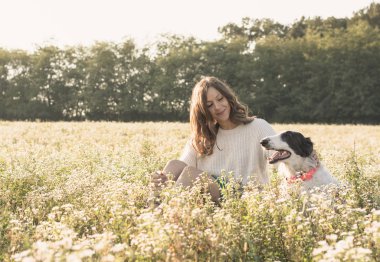 Köpek ile altın sahada oturan kadın