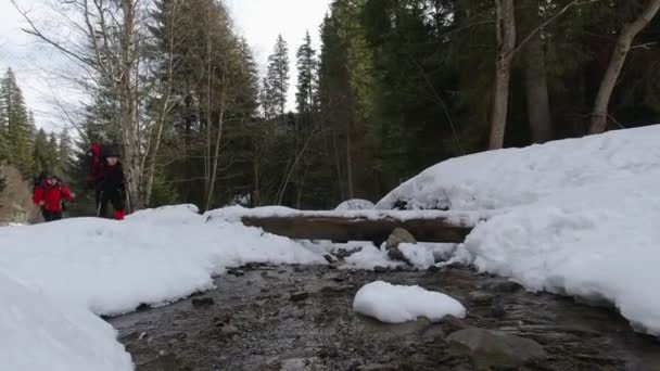 Dois Homens Cruzam Córrego Uma Caminhada Inverno Nos Cárpatos — Vídeo de Stock