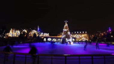 Buz pateni pistinde Noel akşamı. İnsanlar kayıyor.