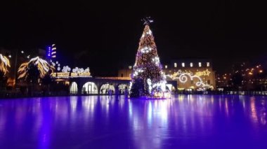 İnsanlar buz pateni pistinde Noel ağacının etrafında dolaşıyorlar.
