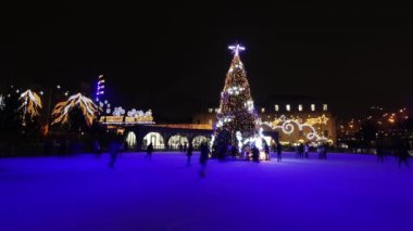 İnsanlar kışın Noel ağacının etrafındaki buz pateni sahasında buz pateni yaparlar..
