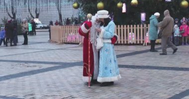 KIEV, UKRAINE 6 HAZİRAN 2018: Noel Baba ve Kar Kızı Kiev 'deki Sophia Meydanı' nda Noel arifesinde telefona bakıyorlar. Noel pazarında, meydanda insanlarla fotoğraf çeken peri masalı karakterleri beliriyor..