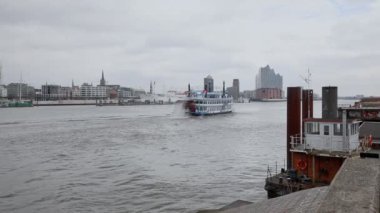 HAMBURG, ALMANY 5 Mart 2017: Aziz Pauli Piers ve Elbphilharmonie arka planında Elbe boyunca bir zevk teknesi gider. St. Pauli Rıhtımı, Almanya 'nın Hamburg limanındaki en büyük çıkarma noktasıdır.