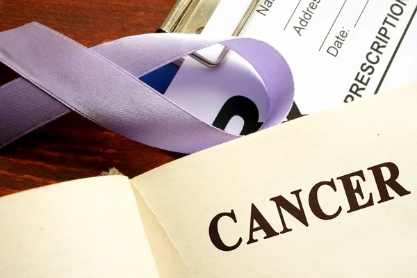 Cancer written on a page and  lavender awareness ribbon. — Stock Photo, Image