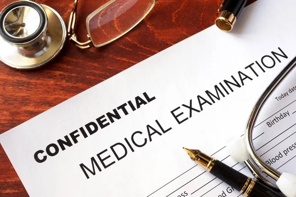 Formulario de examen médico con título confidencial en una mesa . —  Fotos de Stock