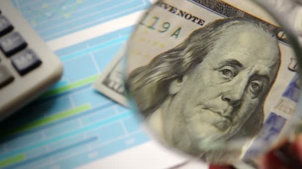 Contexte financier. Le billet en dollar est regardé avec une loupe . — Video