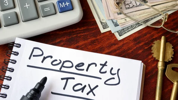 Impuesto sobre la propiedad escrito en un cuaderno y calculadora . — Foto de Stock