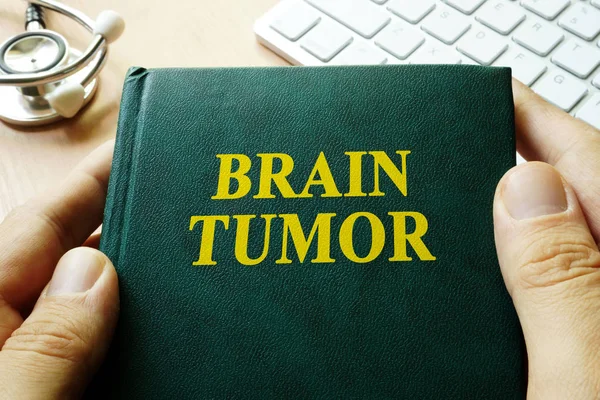 Libro con título tumor cerebral en las manos . — Foto de Stock