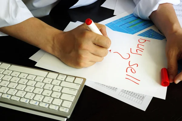 Trader is writing buy or sell in a note. — Stock Photo, Image