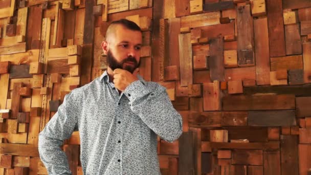 Uomo con la barba pensando vicino al muro di legno . — Video Stock