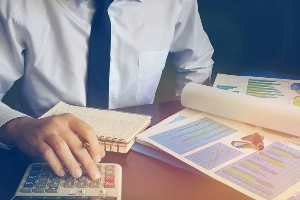 Hombre de negocios usando una calculadora para crear un informe financiero . — Foto de Stock