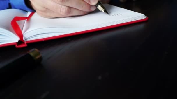 El hombre está abriendo el cuaderno y empezando a escribir por pluma . — Vídeos de Stock