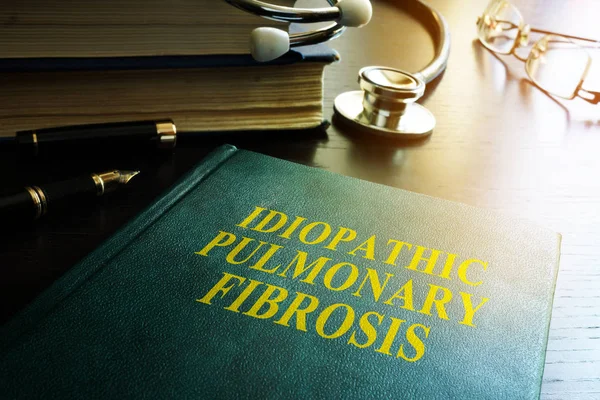Врач держит книгу об Идиопатическом фиброзе легких IPF . — стоковое фото