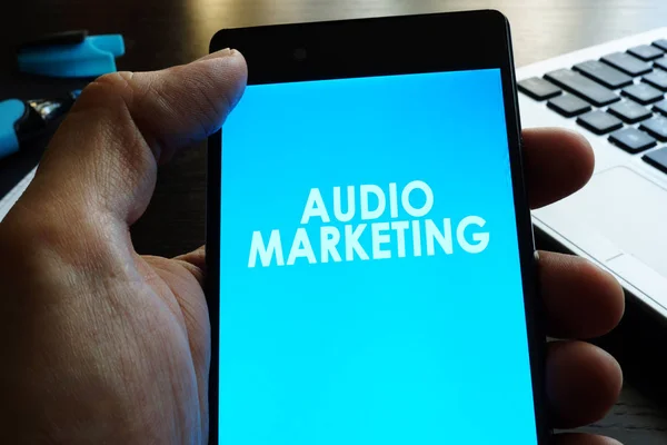 Mann hält Smartphone mit Audio-Marketing. — Stockfoto