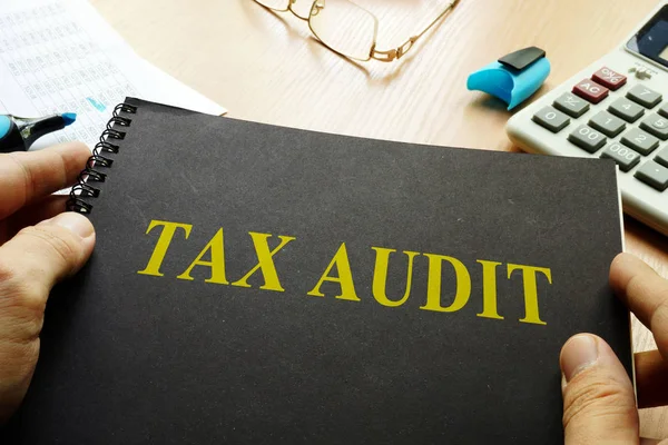 Book about tax audit and calculator on a desk. — Stock Photo, Image