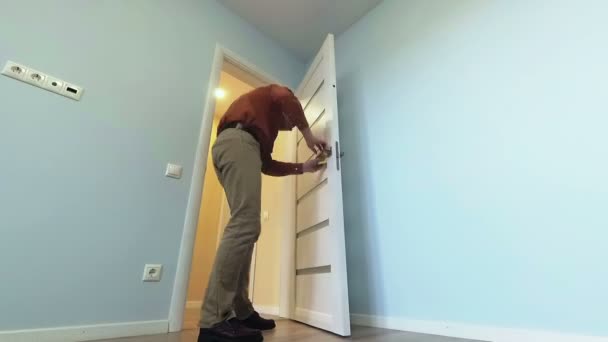 El hombre en el apartamento está limpiando una puerta . — Vídeos de Stock