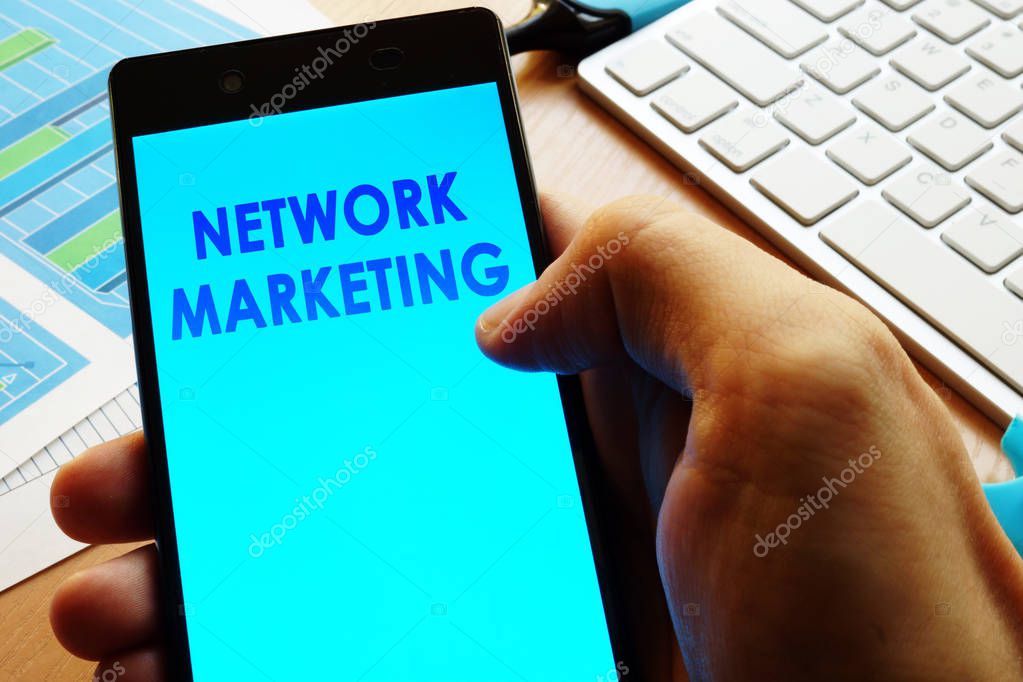 Hand holding smartphone with words network marketing.