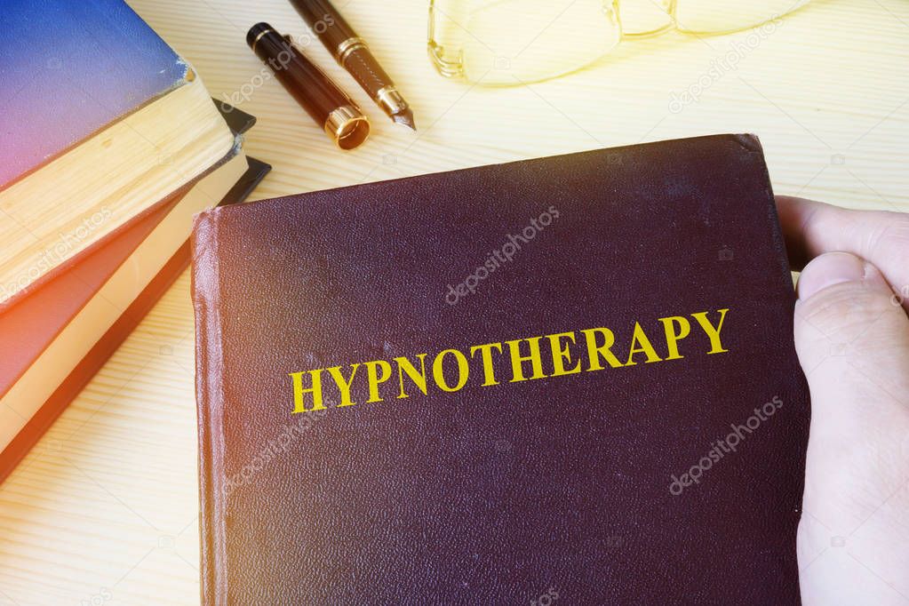 Man holding book with title Hypnotherapy.