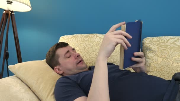 男人躺在沙发上看书 家庭生活 — 图库视频影像