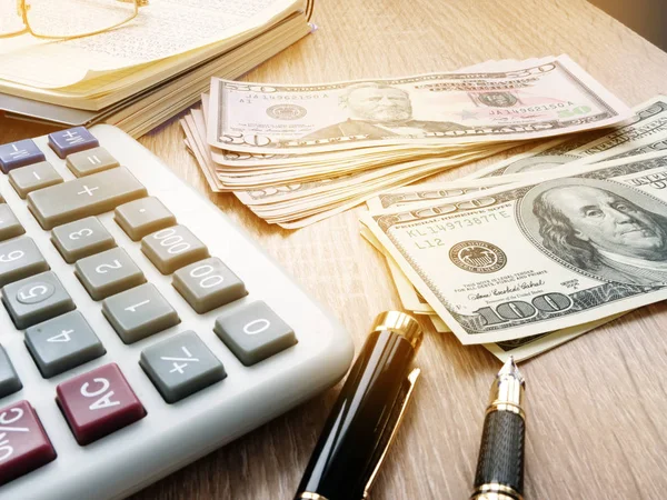 Calculadora, billetes de dólar y libro de contabilidad en una mesa de oficina . —  Fotos de Stock
