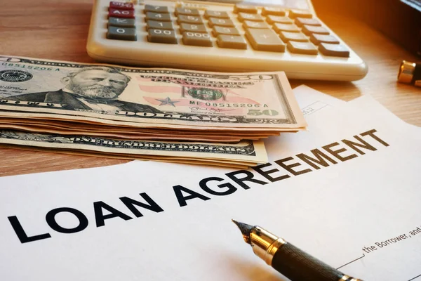 Loan agreement, money and calculator on a desk.