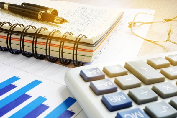 Office desk with accounting book, calculator and financial results. — Stock Photo, Image