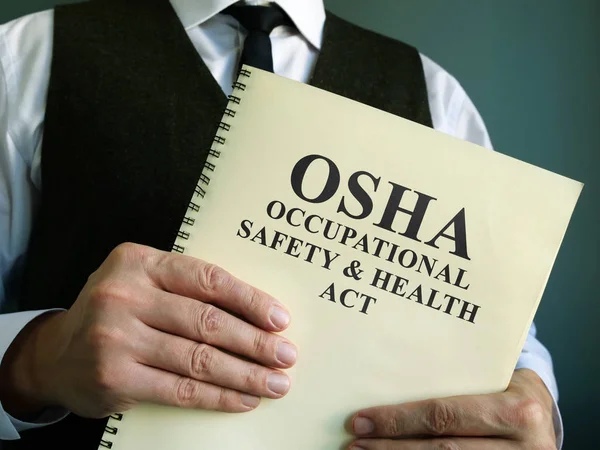 Osha munkahelyi biztonsági és egészségvédelmi törvény a kezében. — Stock Fotó