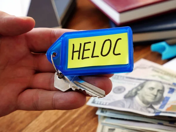 Heloc úvěr koncept. Ruka drží klíč jako symbol nákupu nemovitostí. — Stock fotografie