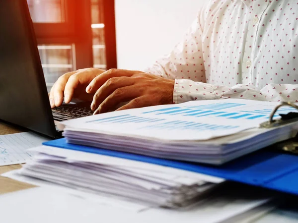Un hombre trabaja en una computadora en la oficina. Montón de documentos de rendimiento financiero . — Foto de Stock