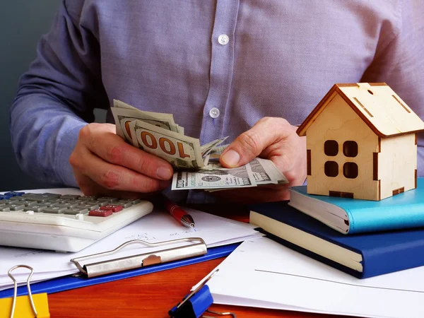 Člověk počítá peníze na hypotéku nebo na koupi domu. — Stock fotografie