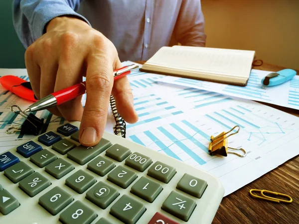 Бухгалтер обчислює фінансові результати з калькулятором і складає бізнес-документи . — стокове фото