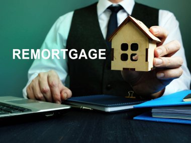 Man holds wooden home and sign remortgage. clipart