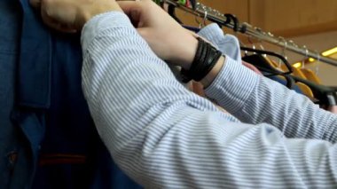 Bir adam giyim mağazasından gömlek seçer. Alışveriş konsepti. Ellerin yakın çekimi.